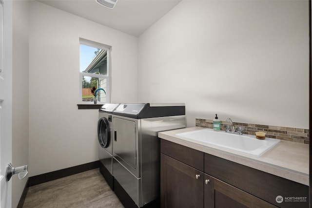 clothes washing area featuring sink, cabinets, and washing machine and dryer