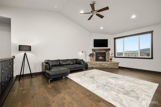 living room featuring ceiling fan, a stone fireplace, dark hardwood / wood-style floors, and lofted ceiling