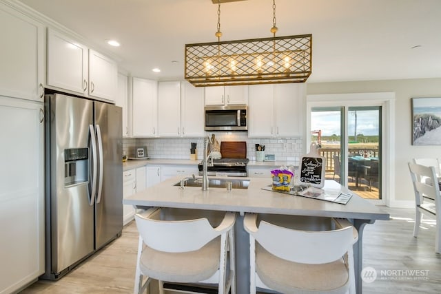 kitchen with tasteful backsplash, pendant lighting, a kitchen bar, white cabinets, and appliances with stainless steel finishes