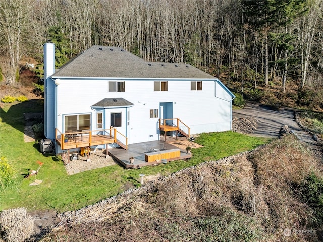 back of house featuring a wooden deck, a lawn, and a chimney