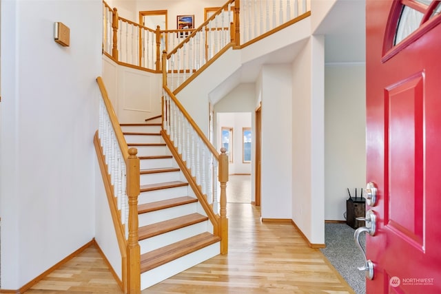 foyer entrance featuring stairs, wood finished floors, baseboards, and a towering ceiling