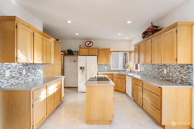 kitchen featuring white appliances, a center island, light countertops, and a sink