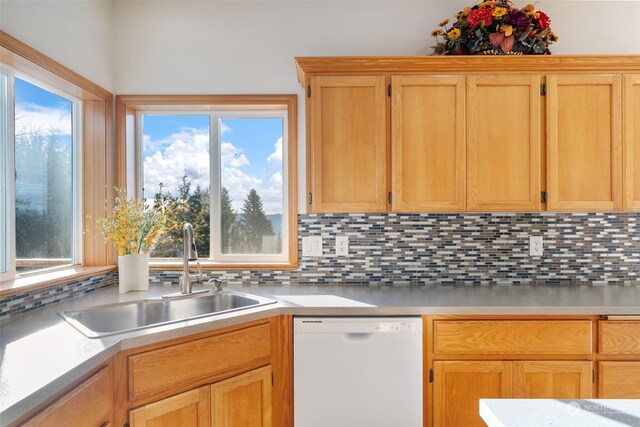 kitchen with decorative backsplash, light countertops, white dishwasher, and a sink