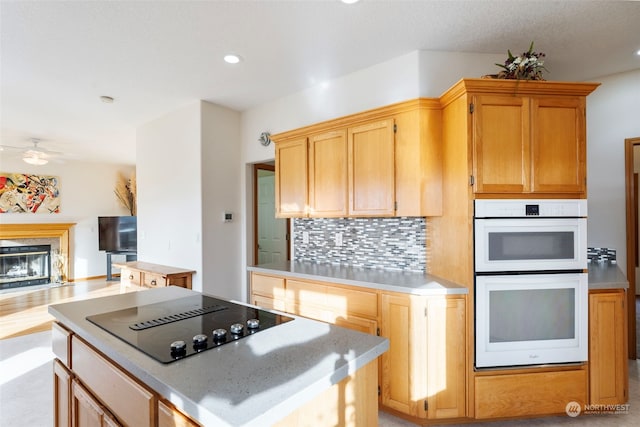 kitchen with a high end fireplace, backsplash, white double oven, black electric stovetop, and light countertops