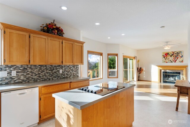 kitchen with tasteful backsplash, a fireplace with flush hearth, dishwasher, and a kitchen island