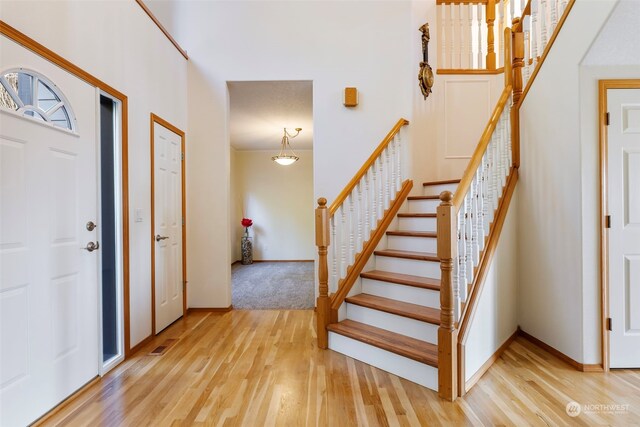 foyer featuring stairway, baseboards, and light wood finished floors