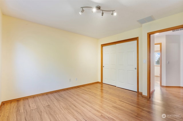 unfurnished bedroom featuring light wood-style floors, visible vents, and a closet