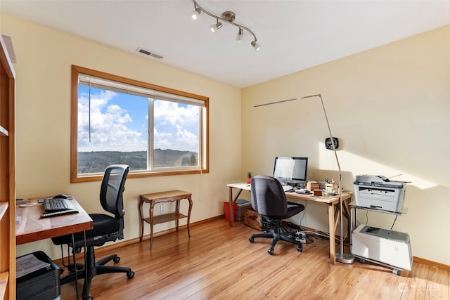 office space featuring light wood finished floors, visible vents, track lighting, and baseboards