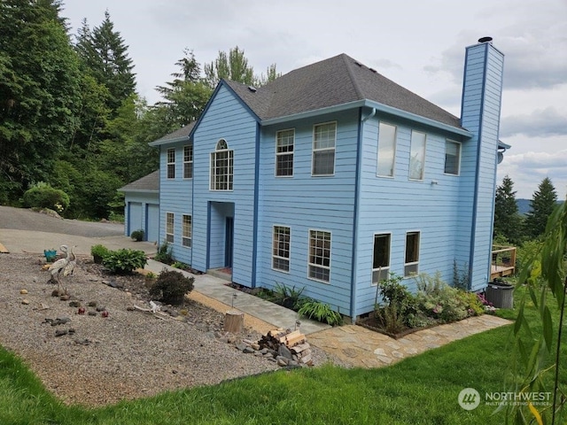 view of front of home with roof with shingles and a chimney