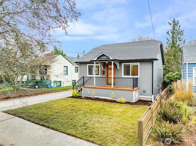 bungalow-style home with roof with shingles, covered porch, and a front yard