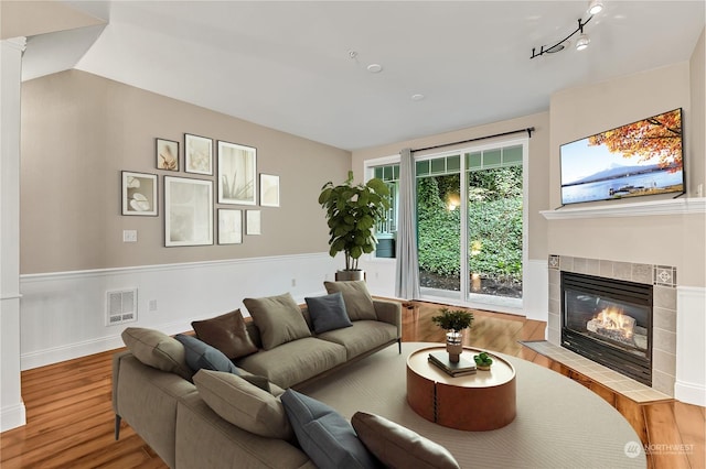 living room with a fireplace, rail lighting, and light wood-type flooring