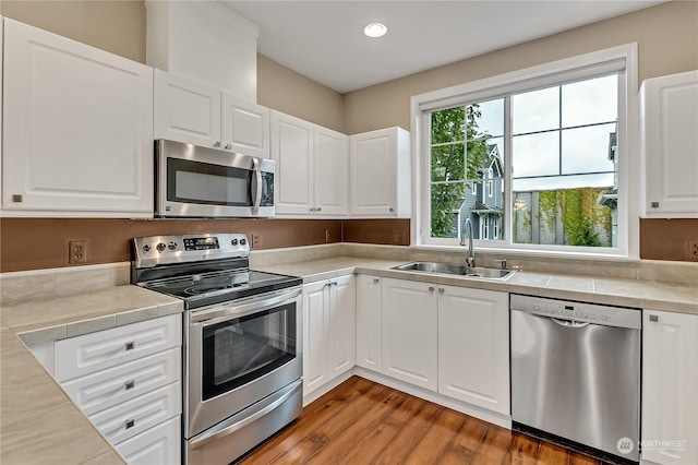 kitchen with dark hardwood / wood-style flooring, white cabinetry, sink, and appliances with stainless steel finishes