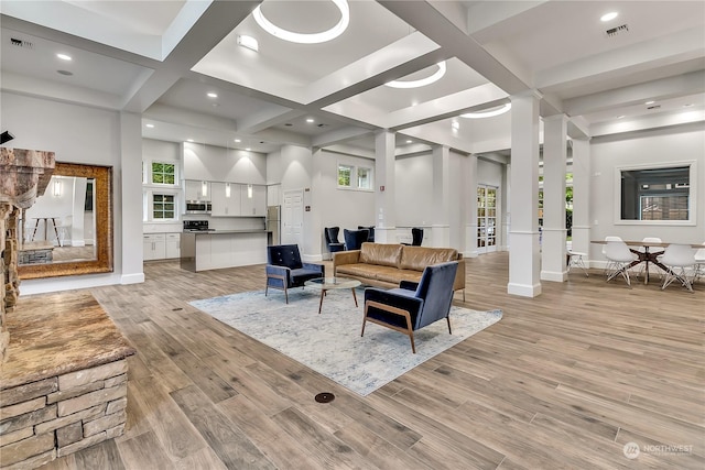 living room with light hardwood / wood-style flooring, a wealth of natural light, and coffered ceiling