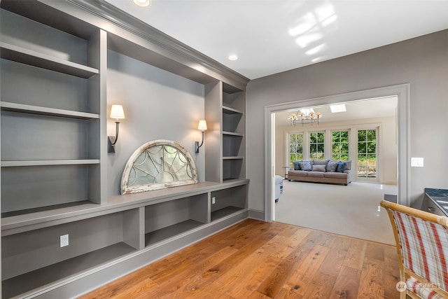 mudroom with an inviting chandelier, hardwood / wood-style floors, and built in shelves