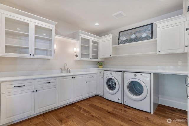 clothes washing area with sink, cabinets, dark hardwood / wood-style floors, and washer and dryer