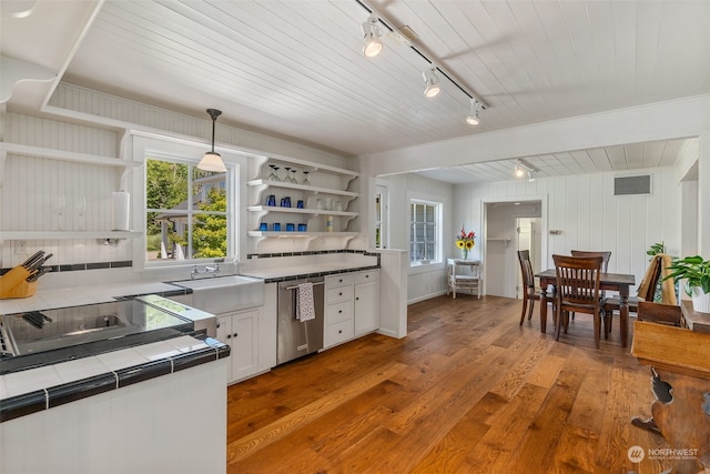 kitchen featuring white cabinetry, tile countertops, hardwood / wood-style flooring, stainless steel dishwasher, and hanging light fixtures