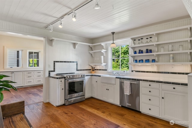 kitchen featuring stainless steel appliances, white cabinets, tile countertops, hardwood / wood-style flooring, and pendant lighting