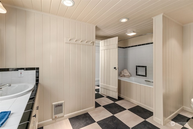 bathroom with heating unit, toilet, vanity, ornamental molding, and a bathing tub