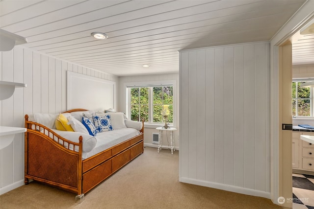 bedroom with light colored carpet, wood walls, and multiple windows