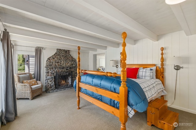 carpeted bedroom with a stone fireplace and beam ceiling