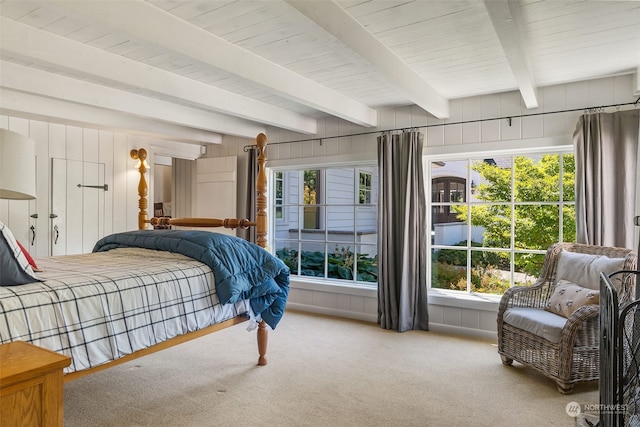 bedroom with wood walls, carpet floors, and beamed ceiling