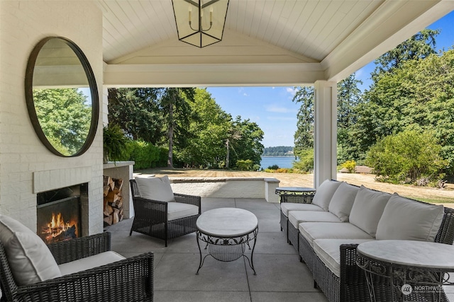 view of patio / terrace with an outdoor living space with a fireplace and a water view