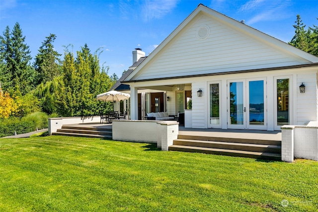 rear view of property featuring a lawn, french doors, and outdoor lounge area