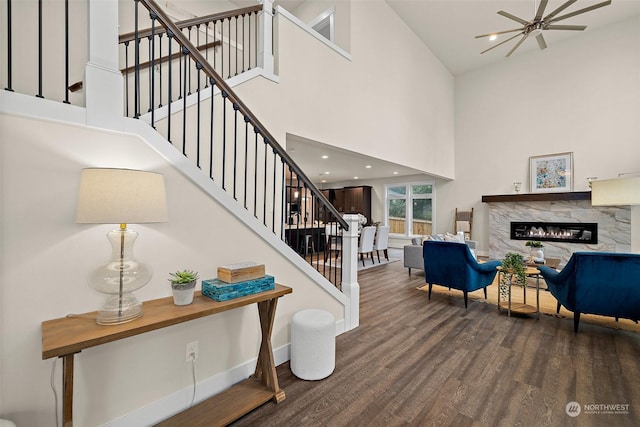 stairway featuring ceiling fan, hardwood / wood-style floors, a high end fireplace, and a towering ceiling