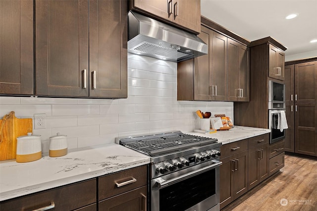 kitchen with ventilation hood, appliances with stainless steel finishes, tasteful backsplash, light hardwood / wood-style flooring, and dark brown cabinetry