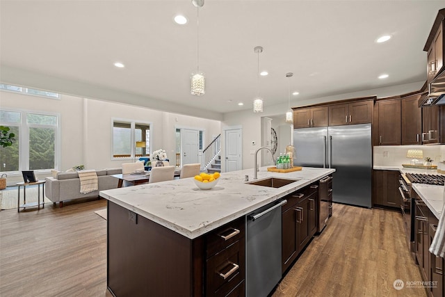 kitchen featuring decorative light fixtures, a kitchen island with sink, dark hardwood / wood-style flooring, high end appliances, and sink