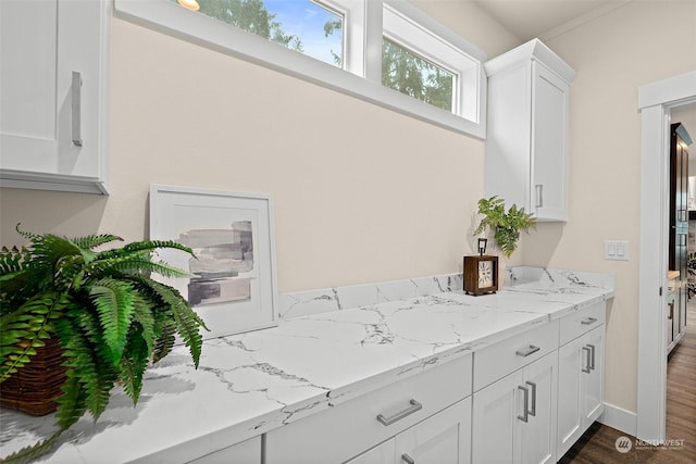 kitchen featuring dark wood-type flooring, white cabinetry, and light stone counters