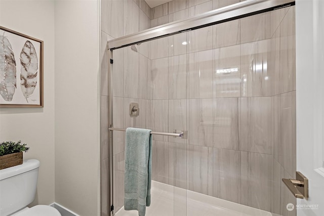 bathroom featuring toilet and a shower with shower door