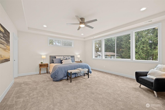 bedroom featuring ceiling fan, light colored carpet, and a tray ceiling