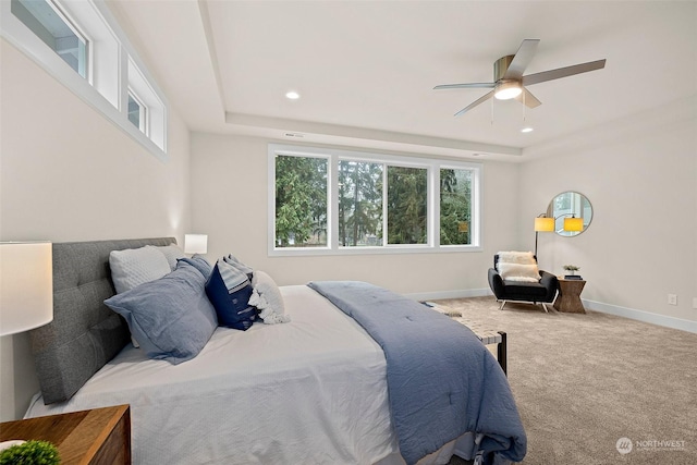 carpeted bedroom with ceiling fan and a tray ceiling