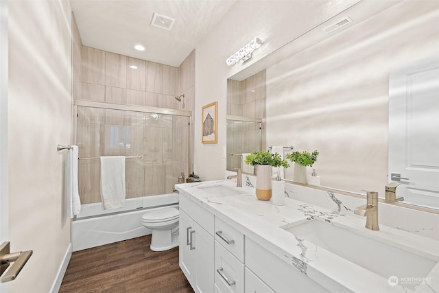 full bathroom featuring toilet, hardwood / wood-style floors, vanity, and shower / bath combination with glass door