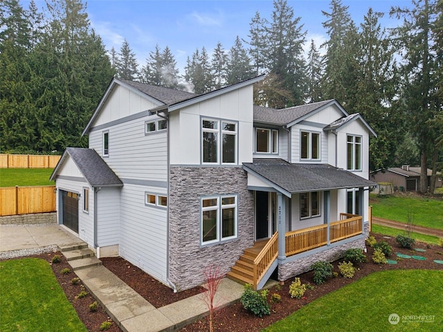 view of front facade featuring a garage, a front lawn, and covered porch