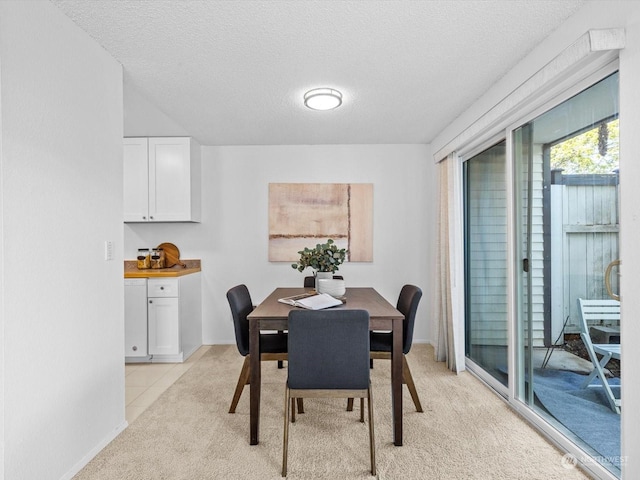 dining room featuring light colored carpet and a textured ceiling