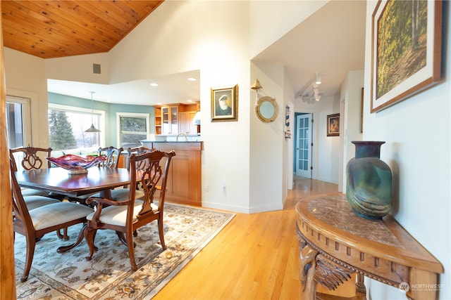 dining room with wood ceiling, high vaulted ceiling, sink, and light wood-type flooring