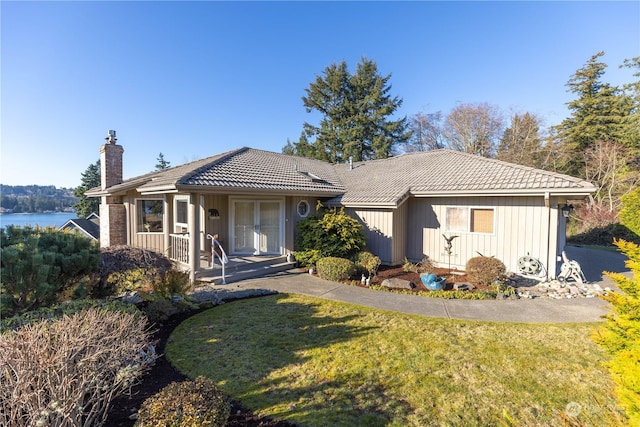 view of front facade featuring a water view, a porch, and a front lawn