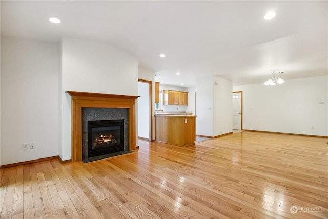 unfurnished living room with light hardwood / wood-style flooring and a notable chandelier