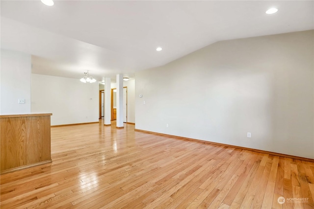 empty room featuring light wood-type flooring, an inviting chandelier, and lofted ceiling