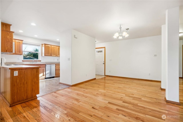 kitchen with a notable chandelier, light hardwood / wood-style floors, stainless steel dishwasher, kitchen peninsula, and hanging light fixtures