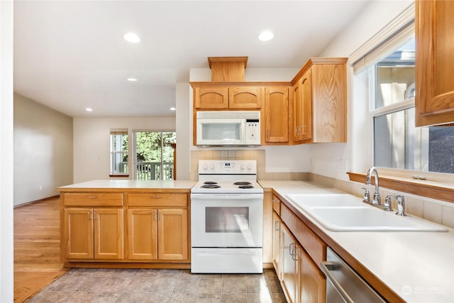 kitchen with sink, white appliances, and kitchen peninsula