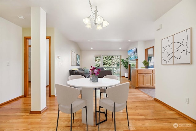 dining area with light wood-type flooring and an inviting chandelier