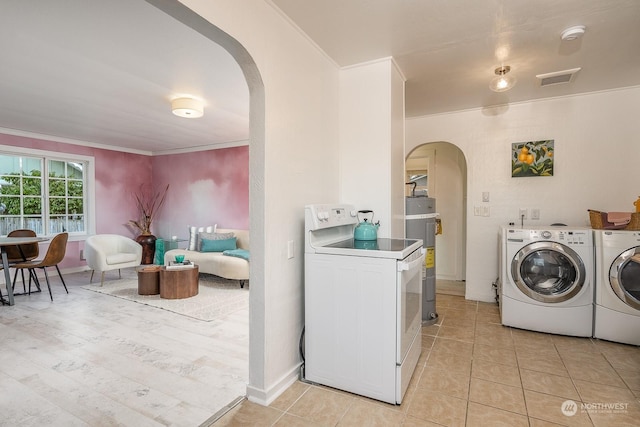 clothes washing area featuring electric water heater, crown molding, light tile patterned floors, and washing machine and clothes dryer