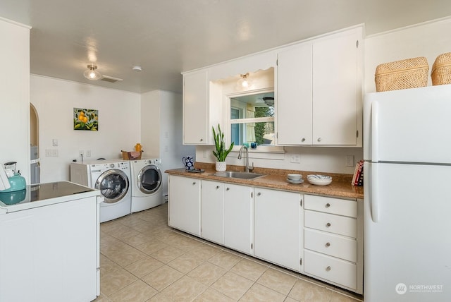 kitchen featuring sink, light tile patterned floors, white cabinets, washing machine and dryer, and white fridge