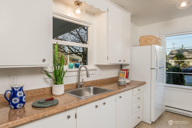 kitchen with white cabinets, a healthy amount of sunlight, sink, and a baseboard heating unit