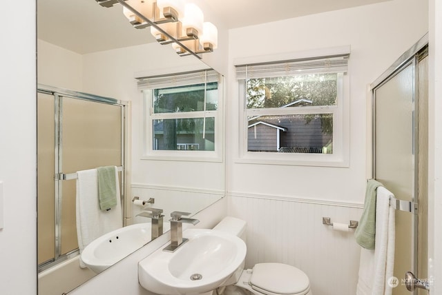 bathroom with sink, an inviting chandelier, an enclosed shower, and toilet