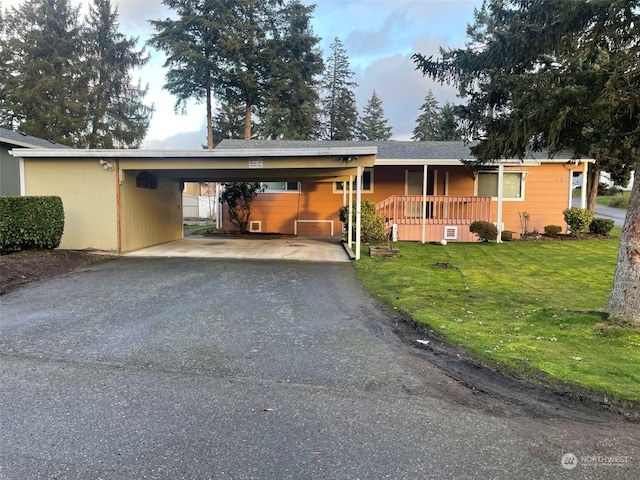 single story home with covered porch, a front lawn, and a carport