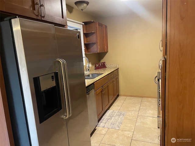 kitchen featuring light tile patterned flooring, light stone countertops, sink, and appliances with stainless steel finishes